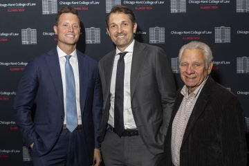 Three men in suits smile for a photo. In the background is Chicago-Kent College of Law branding.