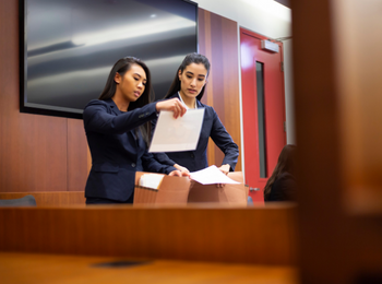 Two students looking at paper in moot court