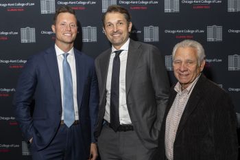 Three men in suits smile for a photo. In the background is Chicago-Kent College of Law branding.